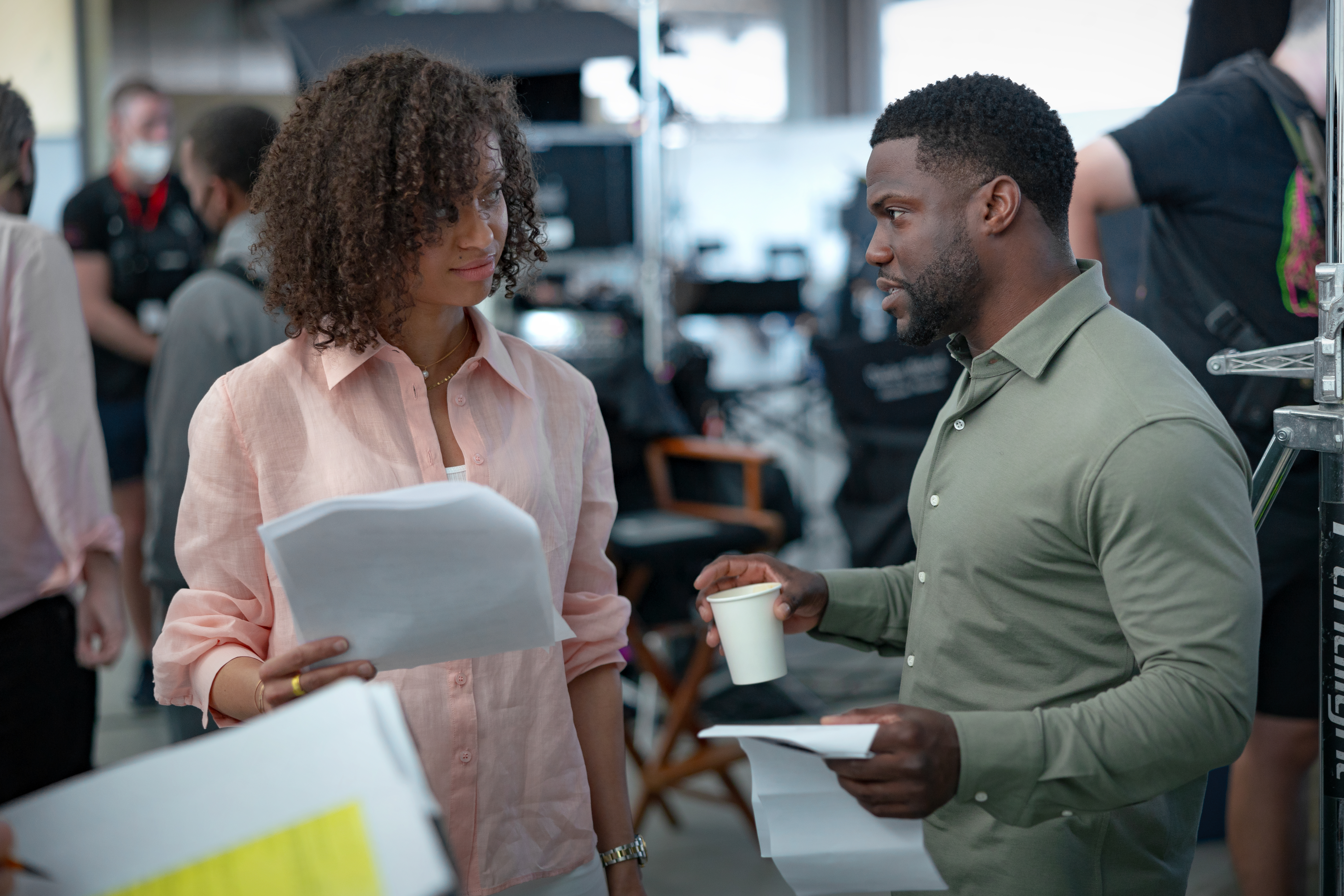 Actor and producer stand on set discussing the script