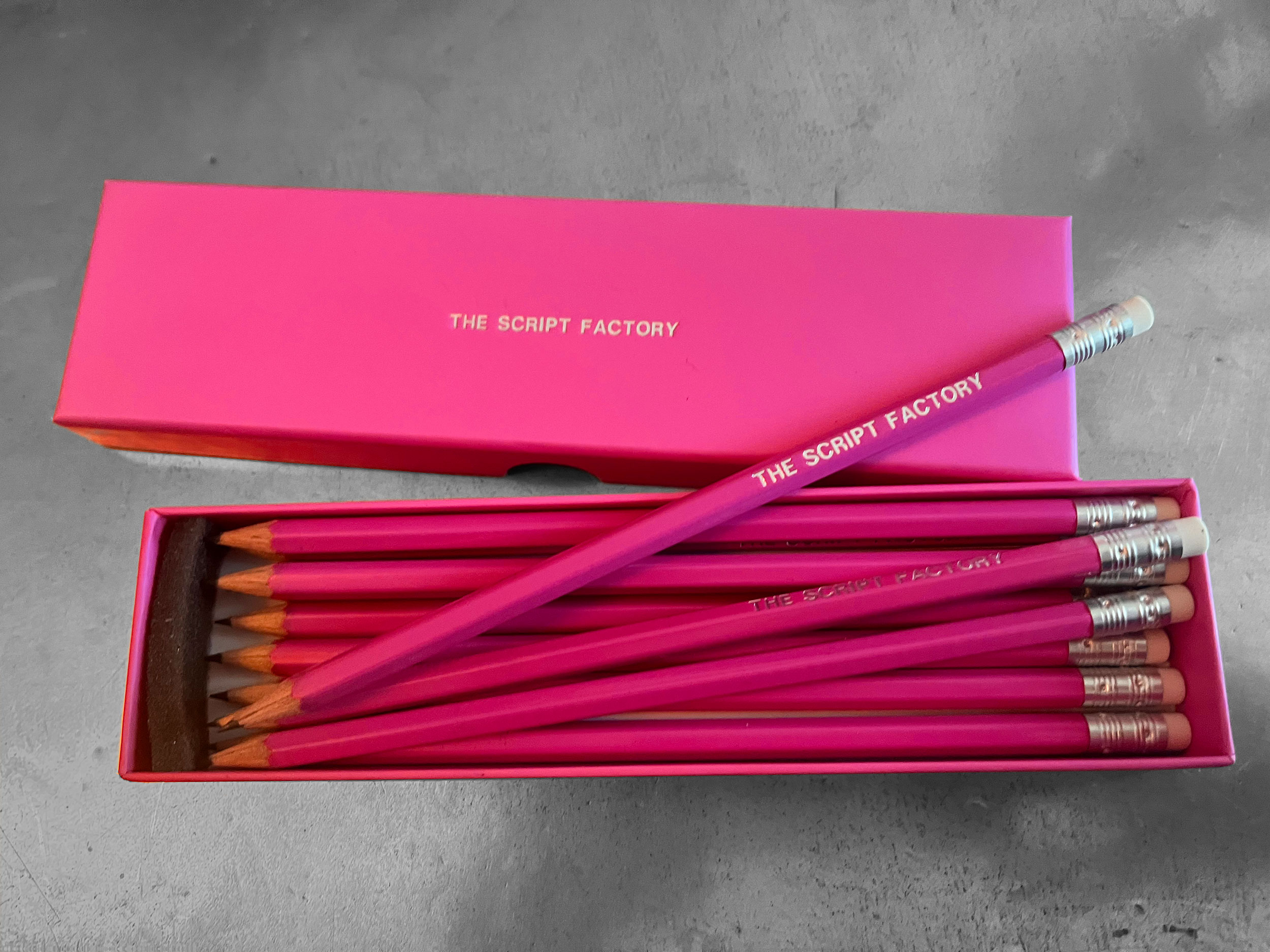 A pink box of pink pencils embossed with 'The Script Factory' in gold lettering