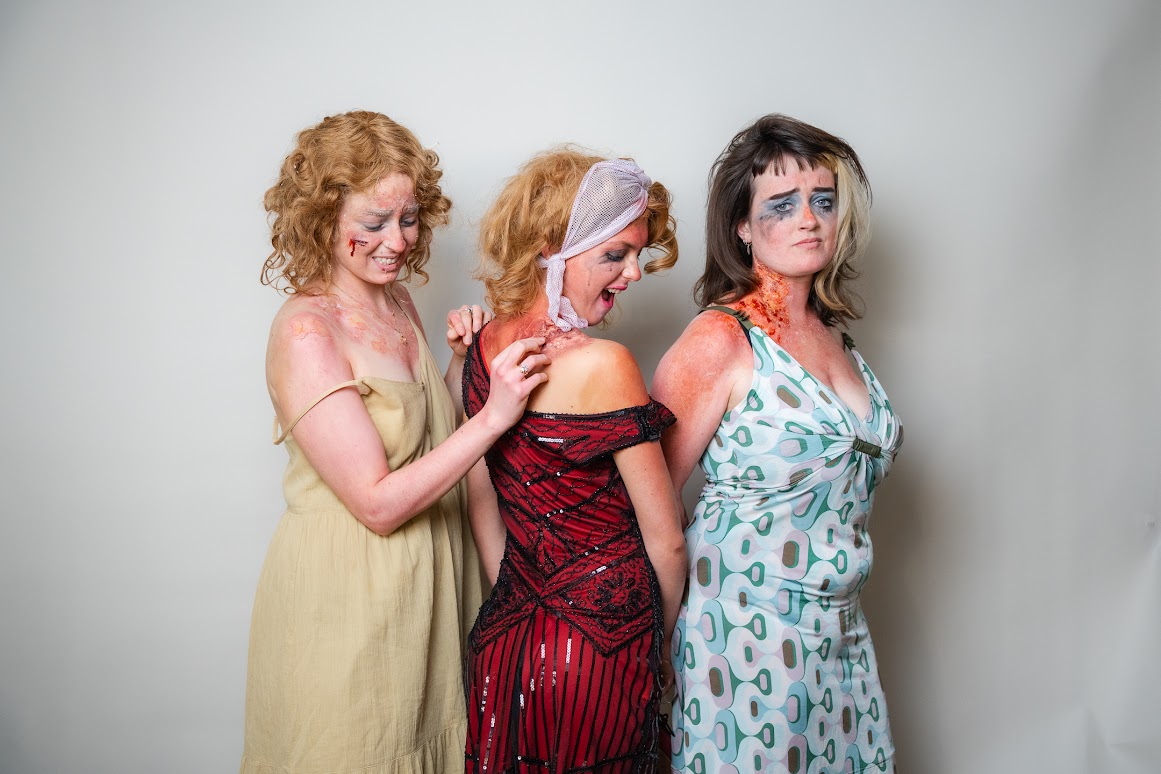 Three women posing for pictures, wearing dresses and zombie make-up