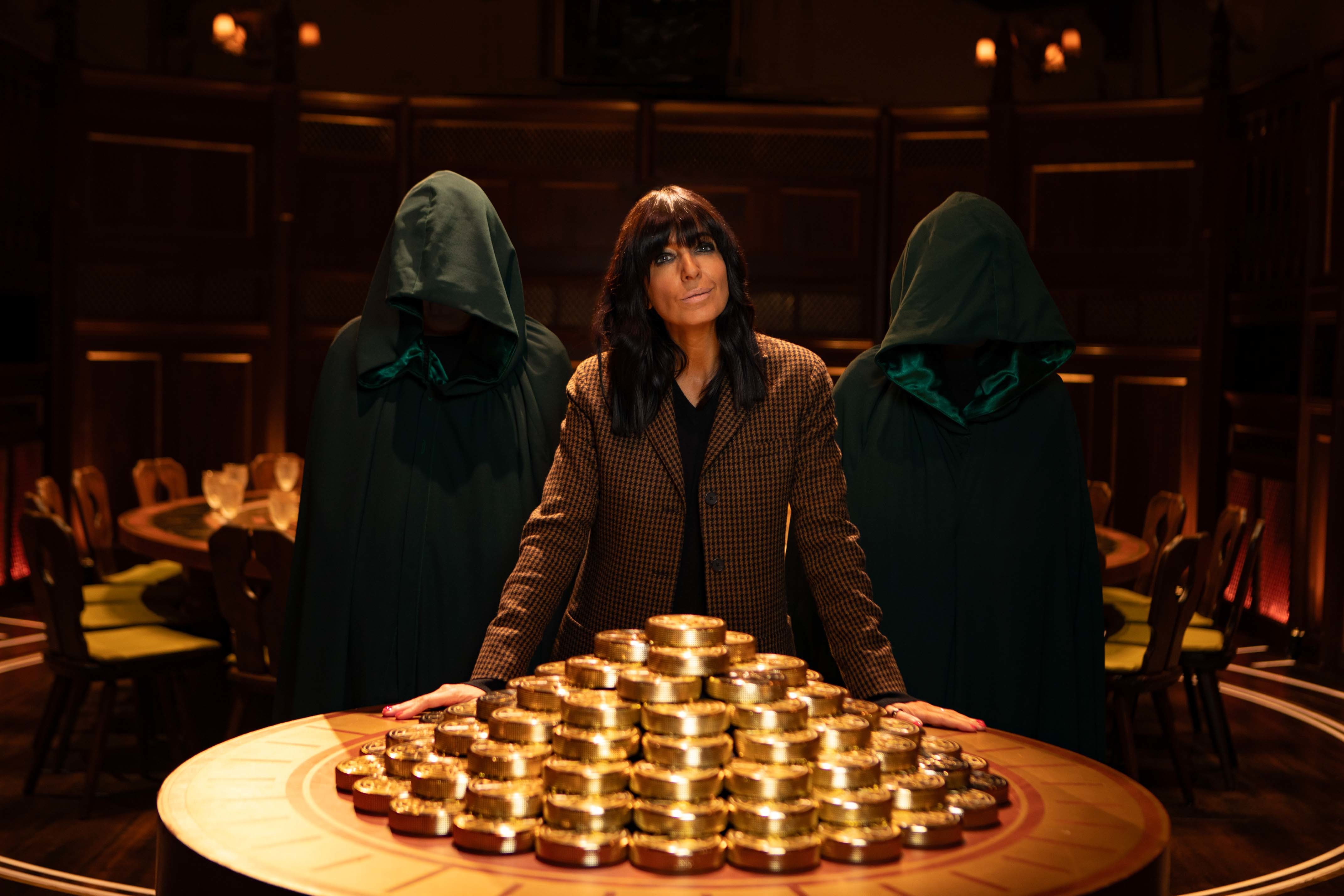 Three people stood behind a table loaded up with golden coins.