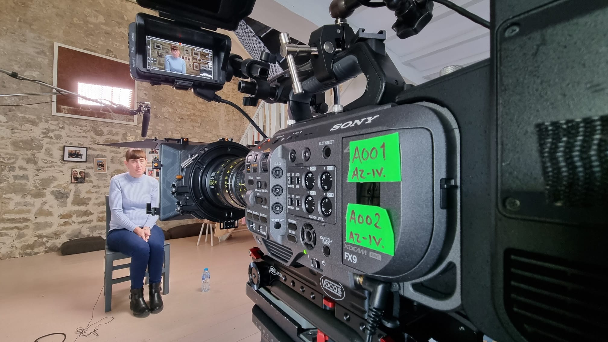 A close up of a cinema camera filming a person sat being recording