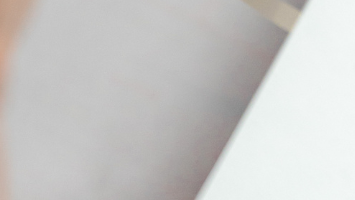 A close-up image of a person's arm resting on the surface of a desk.