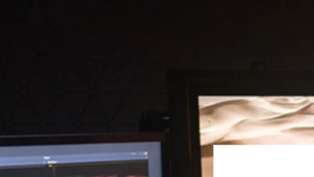 A photograph of a person in front of a desktop computer using a video editing software. Overlaying the image are the Media Cymru and Gorilla Academy logos.