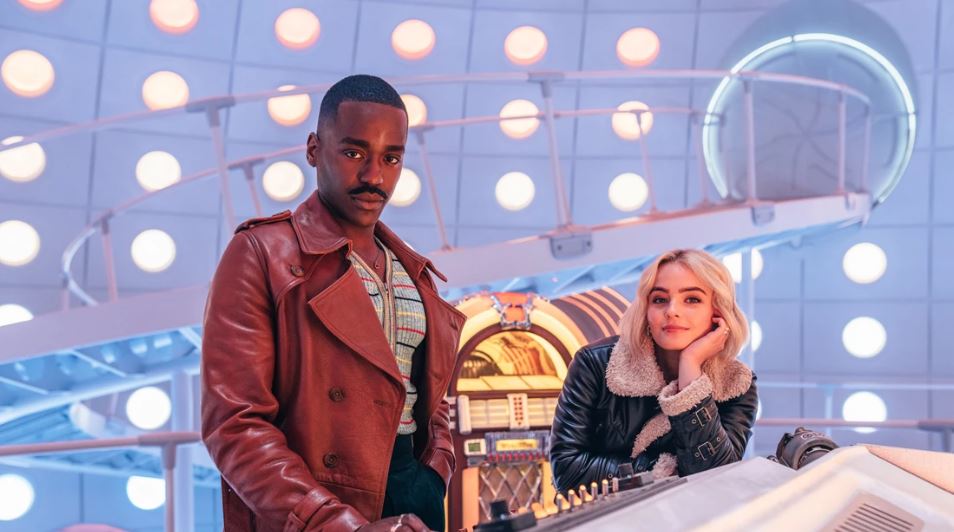 Two individuals positioned in front of a machine, engaged in conversation or observation