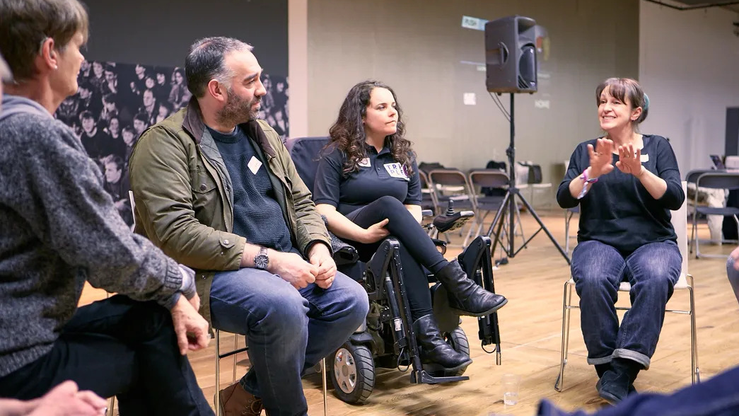 A group of deaf, disabled, autistic and/or neurodivergent professionals gathered in a circle and networking at a DANC event